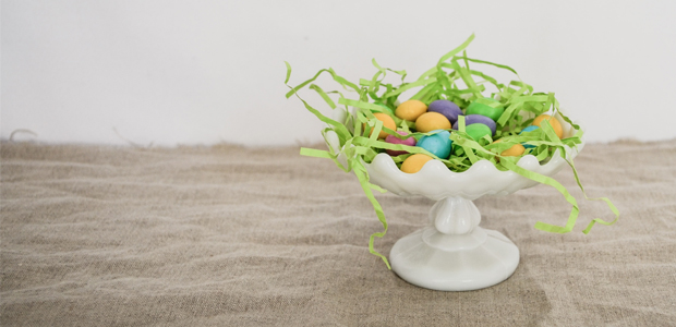 synthetic Easter grass with colourful eggs inside a white bowl