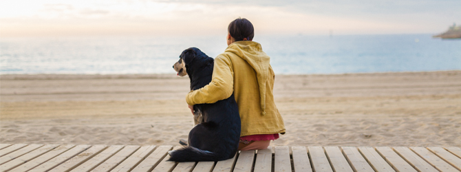 owner and dog gazing out at the ocean